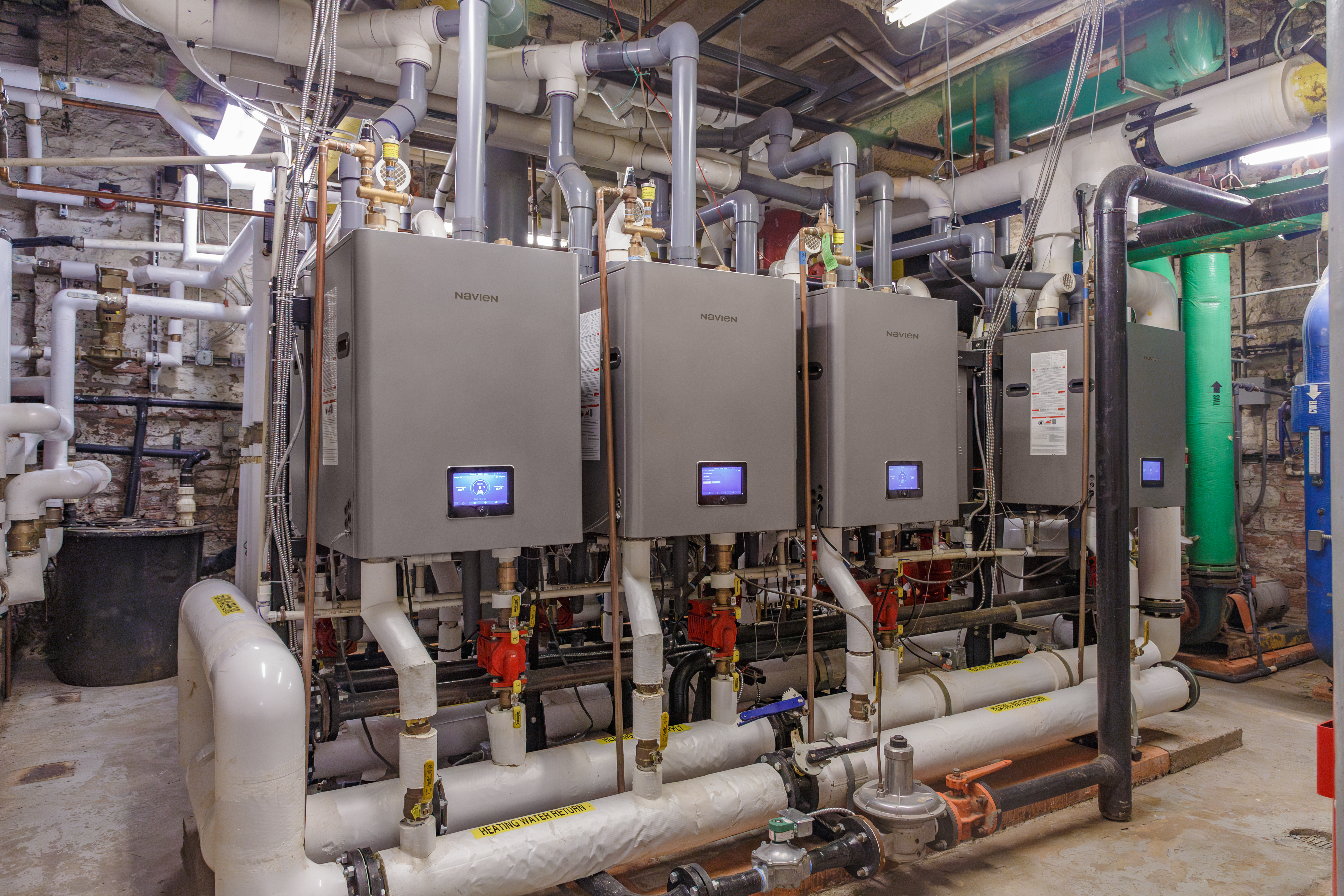 Wall-mounted Navien NFB-399C condensing heating boilers and NPE-240A2 tankless water heaters installed in the basement boiler room of The Oxford Hotel