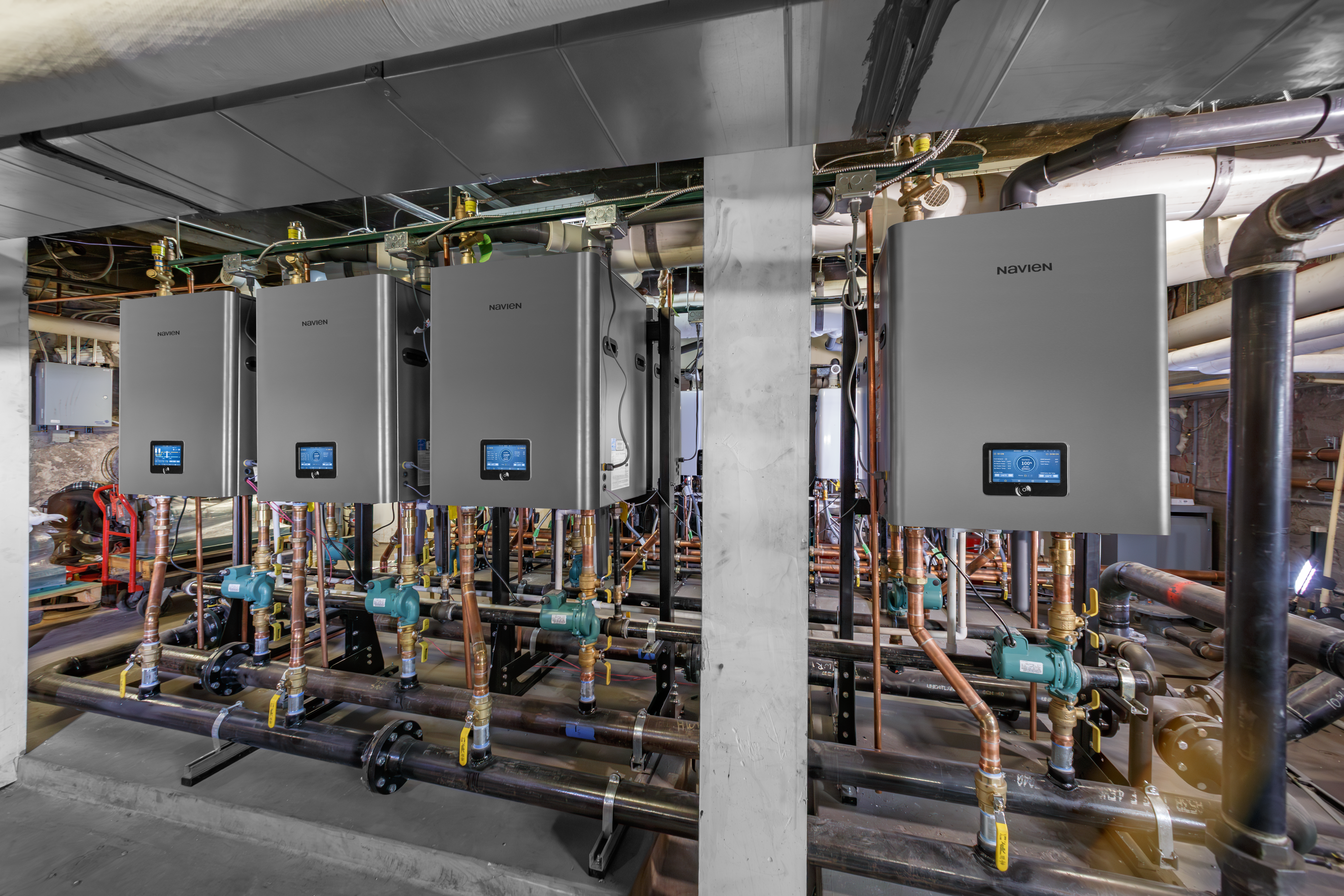 Close-up view of a row of high-efficiency Navien NFB-C commercial heating boilers installed in a commercial mechanical room
