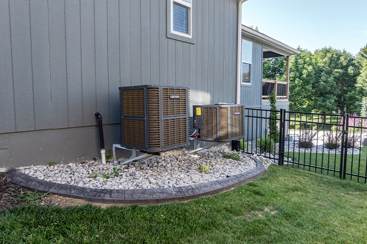 Two outdoor Navien NAZ heat pump units installed in a landscaped yard next to a two-story home