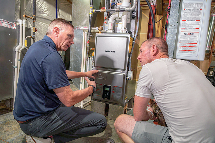 Pointing to the control display of an installed Navien NPF Hydro-furnace during a consultation with homeowner