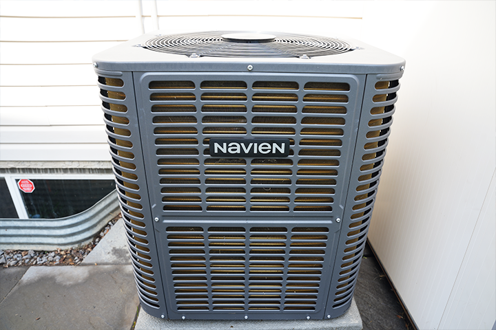 Navien outdoor heat pump unit installed beside a residential home as part of a high-efficiency heating and cooling system.