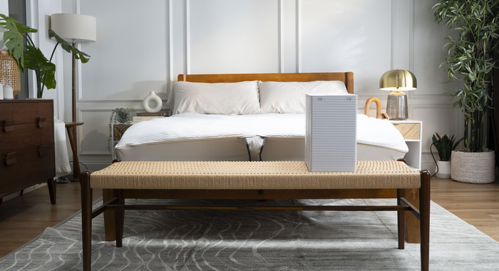 Navien OptiSleep All Season Pro Mattress Pad set up on a bed next to its compact, bedside SleepHub temperature control unit